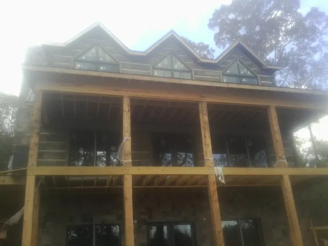 Dormers and porch framing on a large log home under construction — Roof Coating work by our crew in Quincy