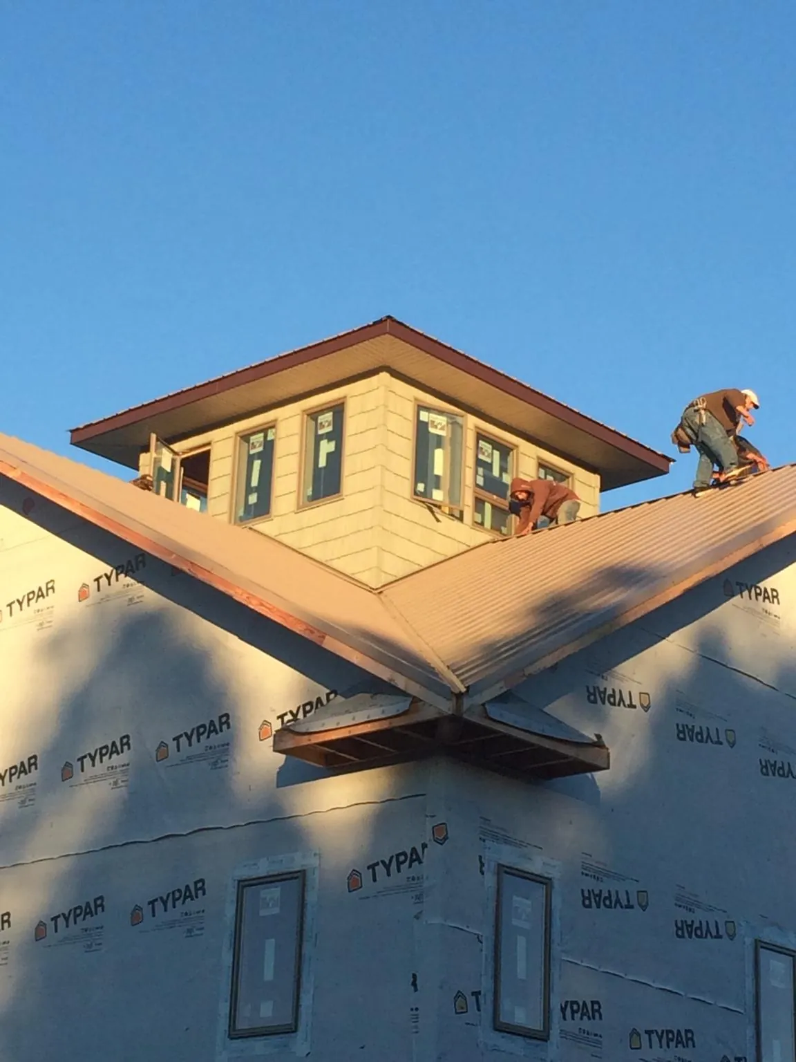 Roofers working around a rooftop cupola on a new metal roof at sunset — Roof Waterproofing in Quincy by Roofing Brothers
